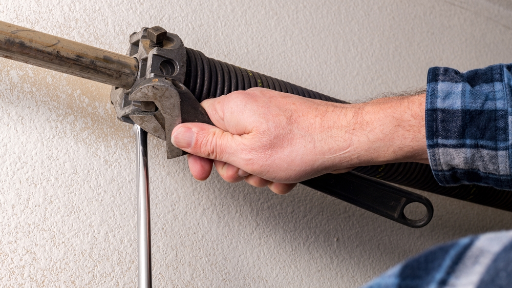 MaintenanceDownOnAGarageDoorByAProfessional Technician performing maintenance and repair work on a residential garage door to prevent rust and long-term damage