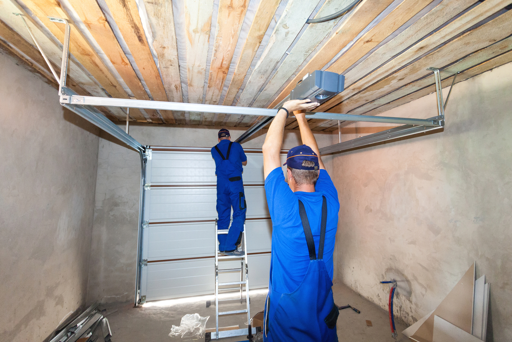 GarageDoorsInstallationworkersInstallingLiftingSystem Garage door installation process showing technicians working on a lifting system and mechanical components in a residential garage.