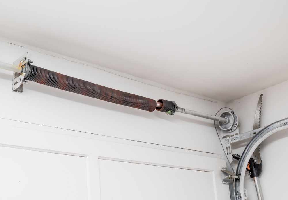 BrokenGarageDoorSpringOrTorsionSpringFromOverheadSectional Broken torsion spring on an overhead garage door system requiring repair.